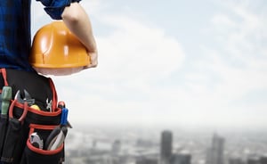 Close up of woman mechanic with yellow helmet in hand against city background-1