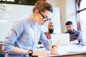 Woman engineer working on blueprint in office with colleagues on background-2